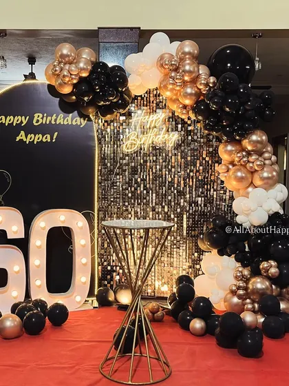 We love a glamorous milestone! For this 60th birthday, we combined a full-stage shimmer wall with a custom 'Happy Birthday Appa' arch, bold marquee numbers, and a rich black and gold balloon garland to create a sophisticated and celebratory atmosphere.
