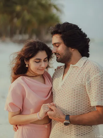 A tender moment on the beach at golden hour, capturing the couple holding hands and sharing a quiet connection.