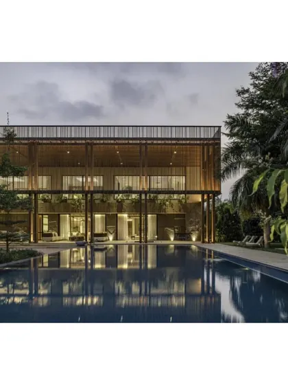 The K House by ADND LLP, a WAF shortlist for House and Villa. This view shows the residence at dusk, with its clean lines, expansive pool, and a wooden screen facade that balances privacy and openness.