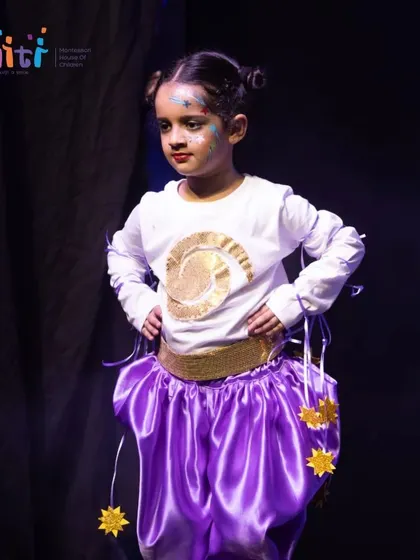 A performer in a beautiful purple and gold costume strikes a confident pose. Our Annual Day is a platform for children to build self-assurance.