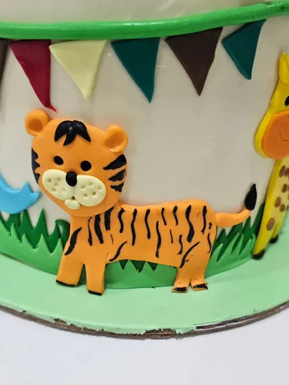 A cute tiger cub fondant decoration from the side of a safari cake. You'll learn how to create these flat decorations to build a scene around your cake.