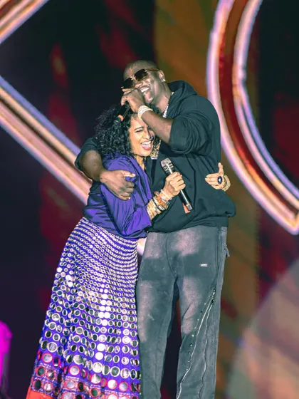 An intimate moment on a grand stage. Akon shares a hug with a guest, showcasing the personal and interactive performances we help facilitate.