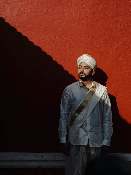 A powerful groom portrait against a bold red wall. The dramatic shadow and his contemplative expression create an artistic and memorable shot that showcases his personality.