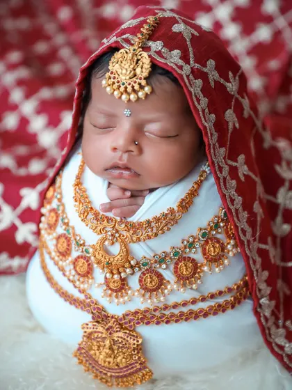 We celebrate cultural heritage with beautifully styled traditional photoshoots. This baby is adorned with intricate, baby-safe jewelry and wrapped in a rich red fabric, creating a timeless and meaningful portrait.