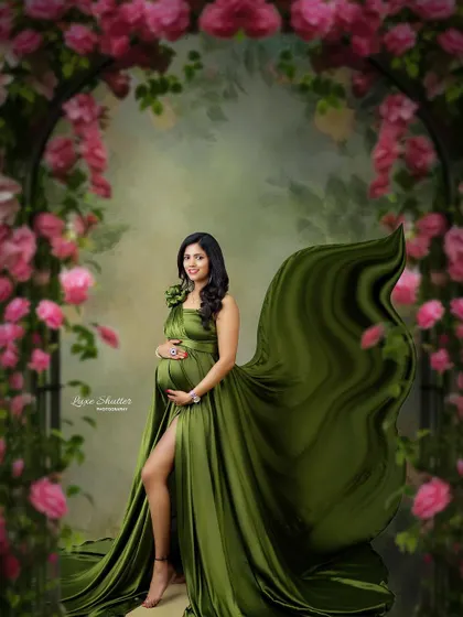 A fine art portrait that feels like a secret garden. The flowing green satin gown and the arch of pink flowers create a stunning and romantic composition.