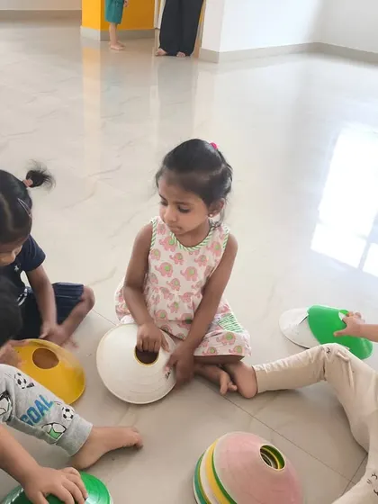 Children sit in a circle and play a game with colorful cones. We use a variety of equipment to make our drills interactive and fun, teaching colors and shapes along the way.