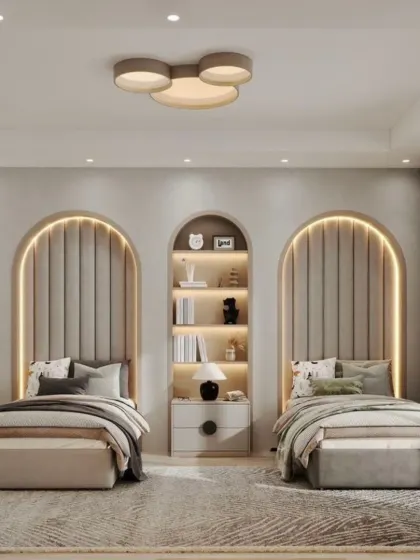 We used arched, backlit niches as headboards in this cozy shared bedroom. A central bookshelf between the beds provides both storage and a display area, making the design practical and stylish.