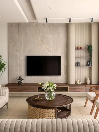 Another angle of the living room, showing the TV unit set against a textured stone panel. The fluted sofa and cane chairs add layers of texture, creating a warm and modern rustic decor.
