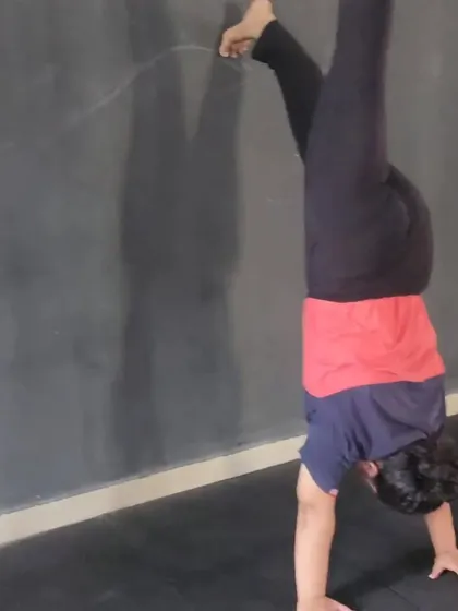 A member practicing a wall-assisted handstand. This is a fundamental step in building the strength and confidence needed for freestanding handstands.
