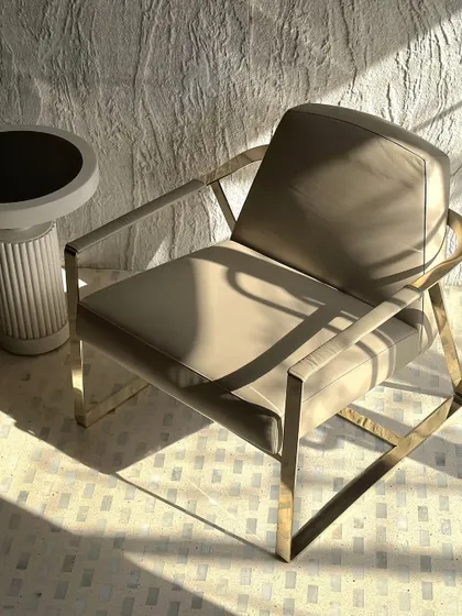 An alternate angle of our metal-framed lounge chair, showing the elegant curve of the armrest. This subtle detail was engineered to soften the chair's geometric structure and enhance its visual lightness.