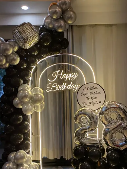 A closer look at the stylish black and silver decor for a 28th birthday. The combination of the lit arch, disco balls, and a personalized message board makes it extra special.
