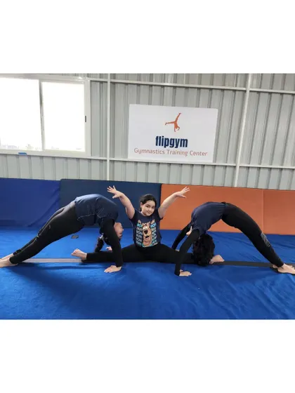 Teamwork makes the dream work. Three of our gymnasts create a partner pose, combining their flexibility in a demonstration of splits and backbends.