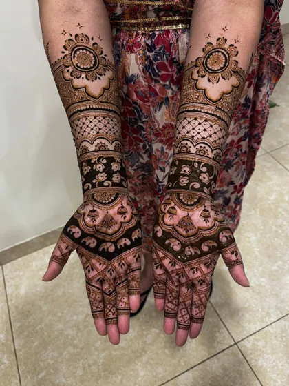 This bridal design features beautiful elephant and jhumka motifs on the palm, with a lovely floral mandala on the back of the hand, offering a complete and ornate look.