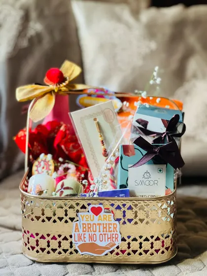 Another angle of the traditional gold basket Rakhi hamper, showing the careful arrangement of festive items.