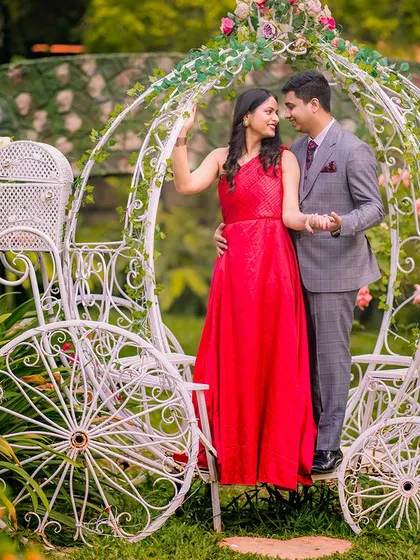 A romantic moment in a Cinderella carriage, with the bride in a stunning red gown. The garden setting adds to the classic, timeless feel of the photo.