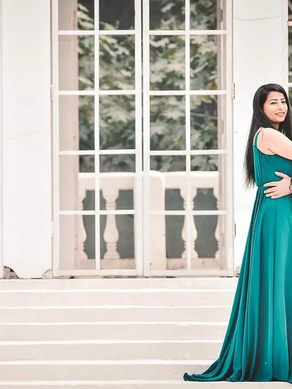 A classic and elegant pre-wedding portrait. The couple stands on a grand white staircase, with the bride in a beautiful teal gown, creating a sophisticated and timeless image.