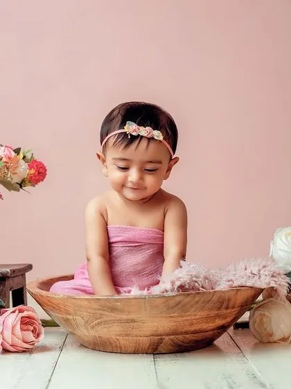 A shy, sweet smile in a bowl of flowers. I use props like this wooden bowl to create cozy and adorable poses for sitter-age babies.