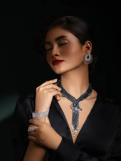 A soft, elegant pose highlighting the diamond bracelet and the unique design of the necklace.