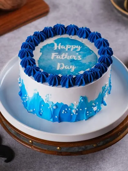 Our "Happy Father's Day" cake, decorated with a blue watercolor effect and a piped border. It's a simple and sweet way to celebrate your dad.