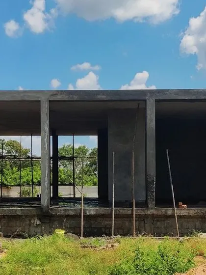 The farmhouse under construction. The raw concrete frame shows the simple, open plan structure and the deep overhangs that are fundamental to its sustainable design, blurring the lines between indoor and outdoor spaces.