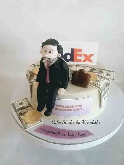 A cake for a workaholic husband at FedEx. The design features a figurine, a briefcase, and edible money.