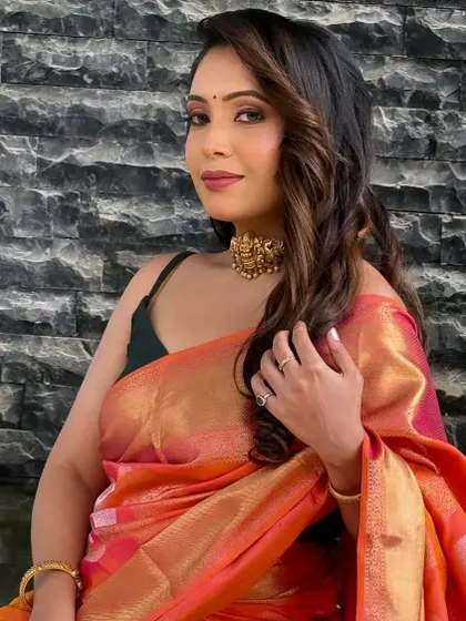 A portrait of a model with her hair styled in glamorous, highlighted waves for a modern saree look.