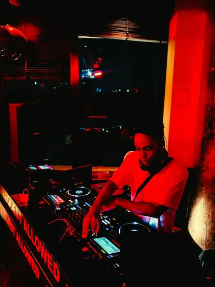 A candid shot of me working the mixer in a dimly lit club. The focus is always on delivering a flawless musical experience.