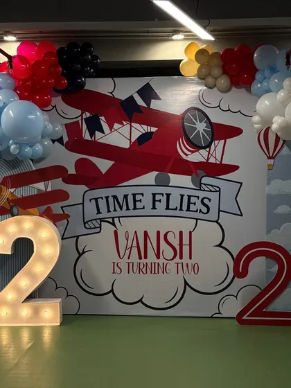 "Time Flies" was the perfect theme for Vansh's second birthday. This airplane-themed backdrop features vintage planes, clouds, and hot air balloons, framed by a red, white, and blue balloon garland.