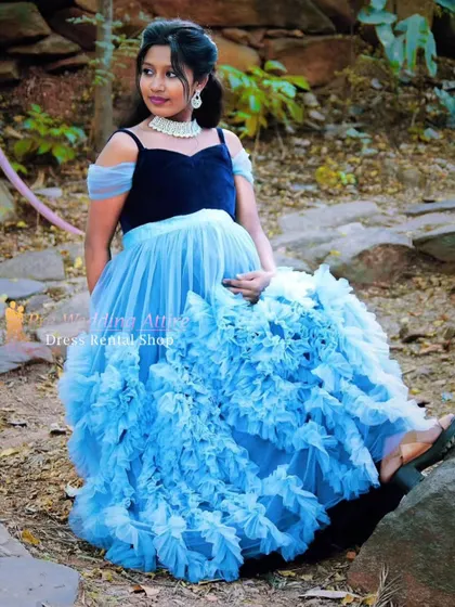 A seated pose in the blue ruffled gown, showing the texture and volume of the skirt up close.
