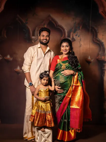 A classic family portrait celebrating their growing family. The family stands together against a traditional backdrop, creating a formal yet warm image that honors their culture and the excitement of a new baby on the way.