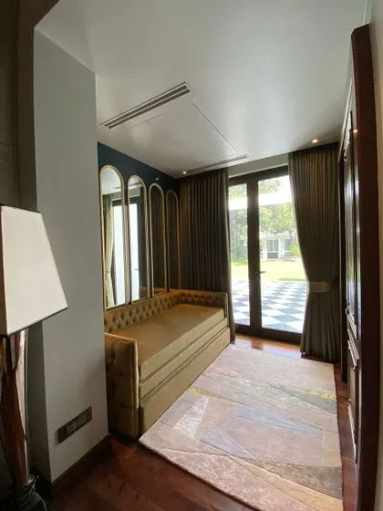 We designed this sitting area to seamlessly connect with the garden. A comfortable sofa-bed is placed against a wall of framed, curved mirrors that reflect the outdoor greenery and expand the sense of space.