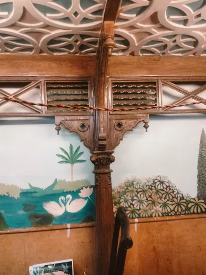 A pair of swans on the water in the Mughal mural, framed by the restaurant's beautiful wooden architecture.