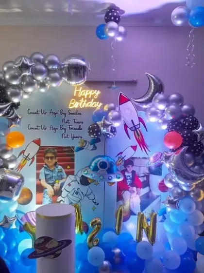 A detailed space-themed birthday party with custom photo backdrops, rocket cutouts, and a balloon arch.