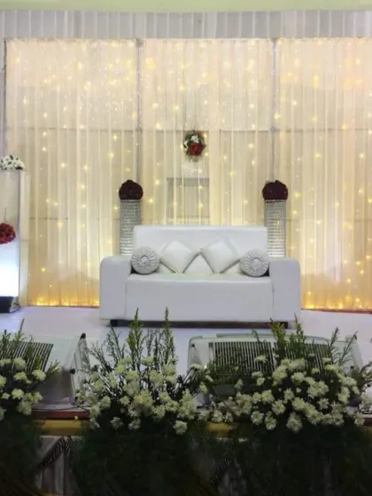 Another view of the clean, white stage decor, with floral arrangements in the foreground.