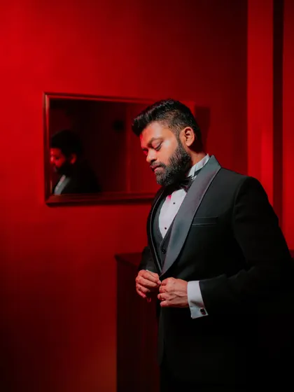 A stylish portrait of the groom buttoning his tuxedo jacket.