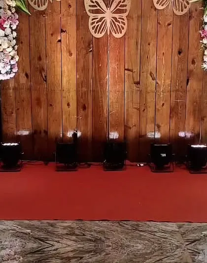A rustic wooden backdrop decorated with floral arrangements and butterfly cutouts. This versatile piece can be used as a photo booth or as part of the stage decor.