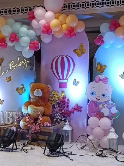 A pastel-themed baby shower with a hot air balloon motif, teddy bears, and butterfly accents against a purple backdrop.