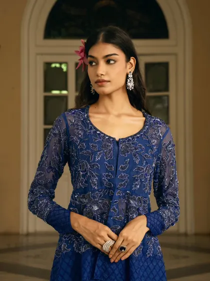 A close-up portrait focusing on the intricate embroidery of the royal blue outfit. The model's calm and poised expression adds to the elegance.