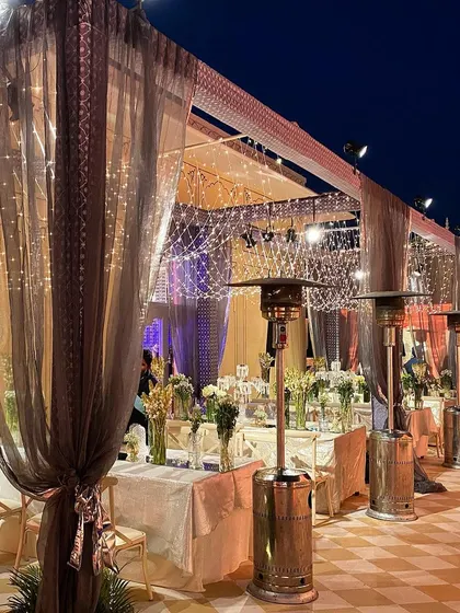 A serene and elegant setup for a Sufi Night. The decor is kept simple and beautiful, with sheer drapes, intricate patterned fabrics, and the magical glow of fairy lights creating a peaceful and soulful ambiance.