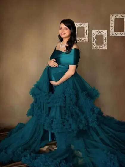 A stunning teal ruffled gown photographed in the studio. The rich color and cascading layers of tulle create a luxurious and elegant look that beautifully frames the baby bump.