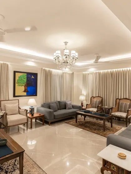 We designed this living room with a tranquil palette of cream and wood. The space is furnished with elegant pieces from Rosabagh, complemented by a large, vibrant painting that adds a pop of color. The overall effect is one of sophisticated calm.