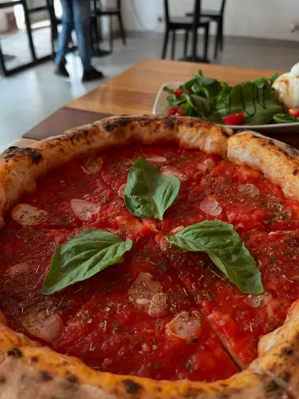 Our Marinara pizza on the table, with a fresh salad in the background. A perfect light meal.