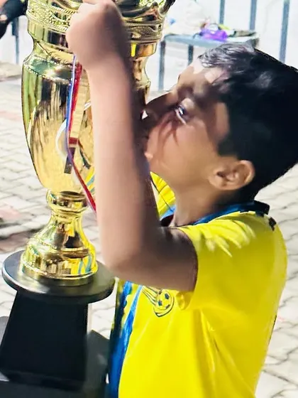 A young player kisses the trophy. This passion and love for victory is what we aim to inspire.
