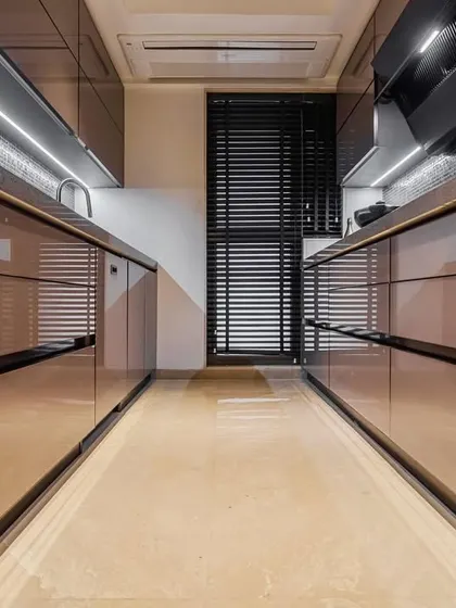 A sophisticated parallel kitchen with brown acrylic cabinets and under-cabinet lighting. The layout is perfect for a seamless cooking process, with everything organized and within easy reach.
