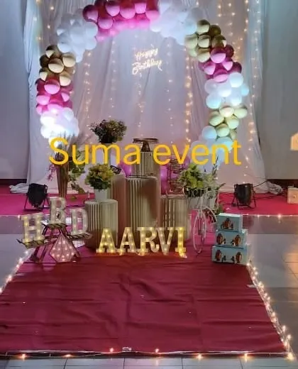 An elegant and modern first birthday setup for Aarvi. This design features a circular balloon arch with fairy lights, gold pedestals, and light-up marquee letters for the name and "HBD".