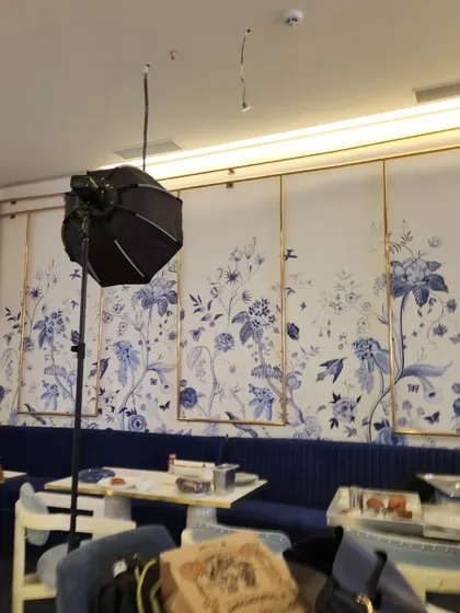 An elegant floral mural with delicate blue flowers and birds, designed for a sophisticated cafe interior. The artwork is framed by gold trim, integrating seamlessly with the high-end decor.