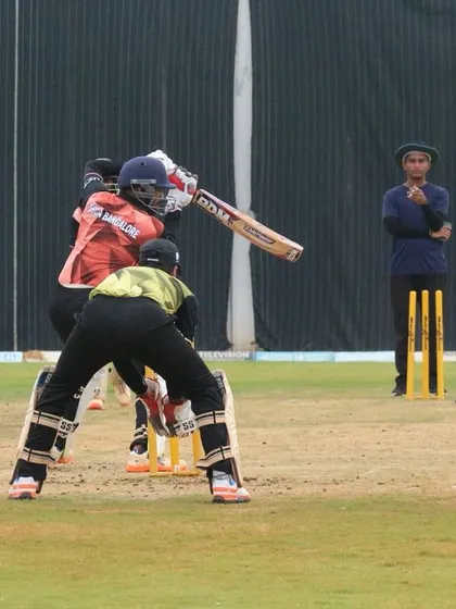 A view from behind the batter during a practice match, showing the full setup with fielders.