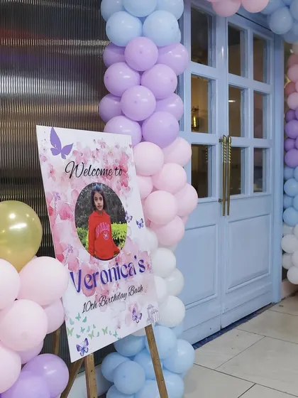 A personalized welcome sign at the entrance, featuring a photo of the birthday girl, invites guests to her glamorous 10th birthday bash.
