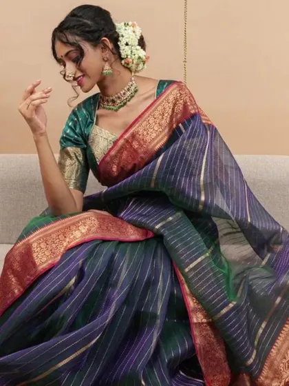 This model is seated, wearing a beautiful silk saree and a green blouse, accessorized with a matching green beaded necklace.