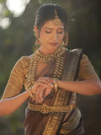 A close-up of the model looking at her hands, a classic and elegant pose in traditional Indian photography. The soft outdoor light is perfect for this kind of shot.